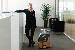 Renolder som poserer sammen med en renholdsrobot