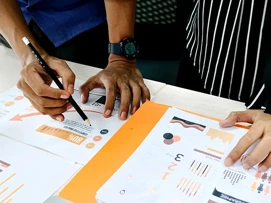 Noen som er lent over et bord med masse papirer og som skriver