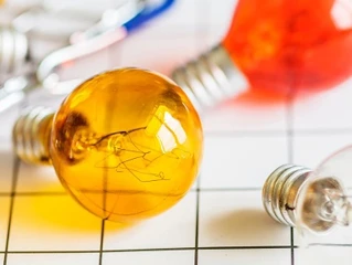 Fargerike glødepærer på rutet underlag med fokus på en gul pære i forgrunnen.