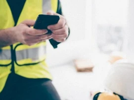 Person i gul HMS-vest som trykker på mobiltelefon