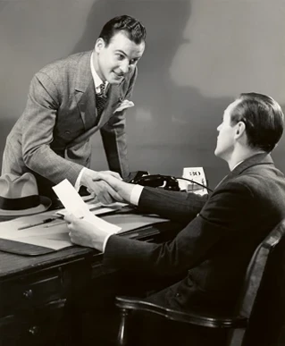 Bilde i svart/hvit av to personer fra 1950-tallet på et tidsriktig kontor.