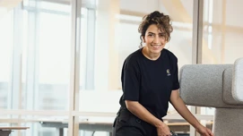 Kvinnelig renholder som rister en pute på et kontor