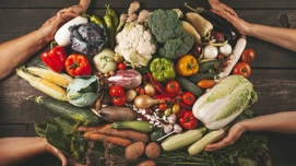 Hender som former et hjerte med grønnsaker.