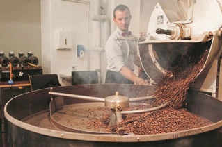 Fra et kaffebrenneri, en som heller kaffebønner i en stor maskin