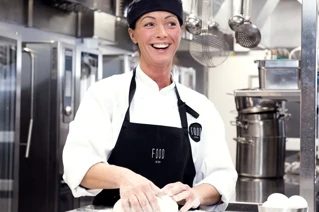 Smilende kvinnelig kokk som baker