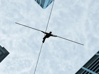 En person som går på line mellom to bygg, sett i froskeperspektiv