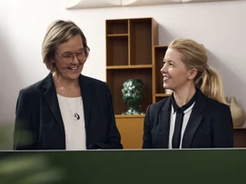 To Coor ansatte som står i en resepsjon