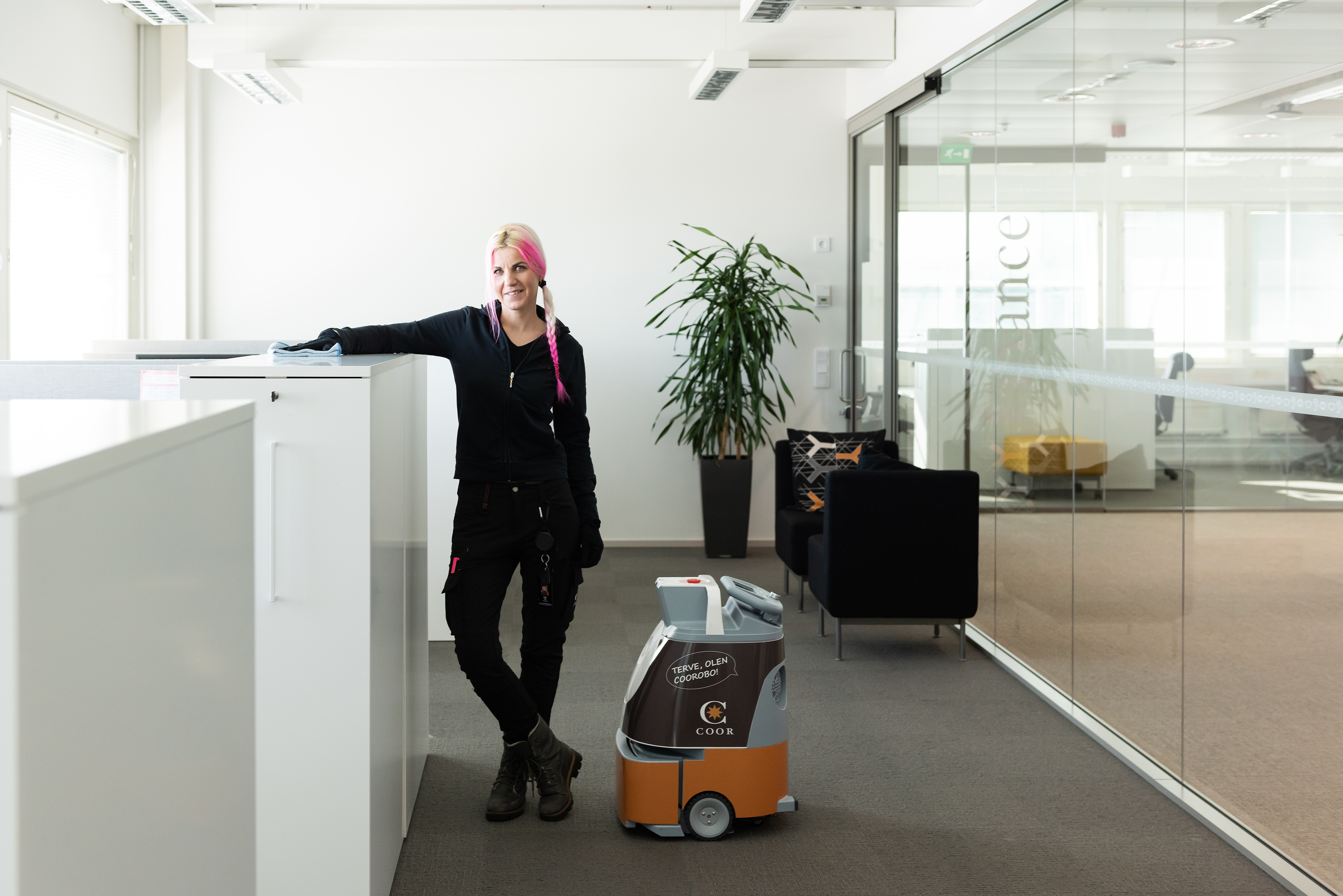 Dame på kontor med renholdsrobot