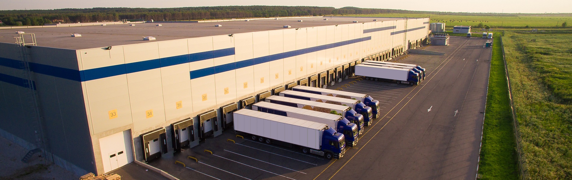 En stor terminal med lastebiler plassert i et grønt beitelandskap | Eiendomsservice på de fleste typer eiendommer | Coor