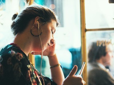 En dame som hører på hodetelefoner | Coor