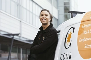 Vaktmester som lener seg mot en Coor-brandet varebil
